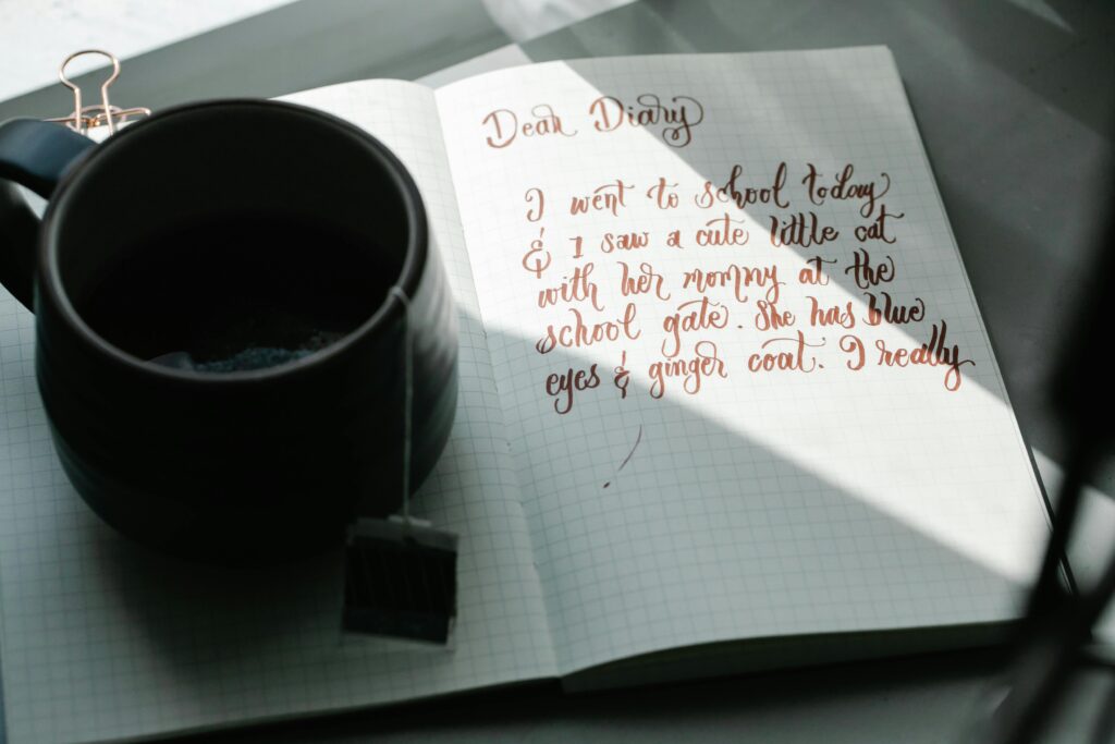 A handwritten journal entry beside a cup of tea on a sunny day.