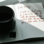 A handwritten journal entry beside a cup of tea on a sunny day.
